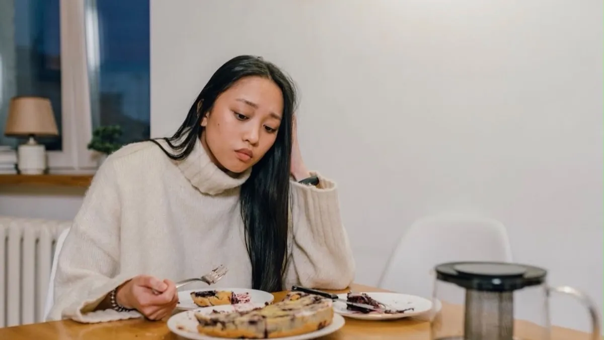 Mulher pensativa diante de um doce, ilustrando o food noise — o pensamento constante sobre comida