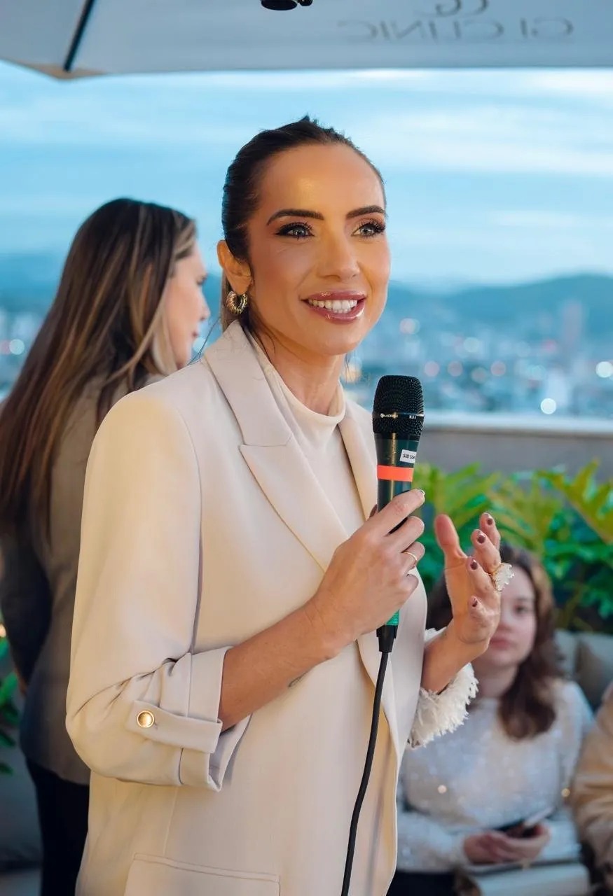 Andressa Langlois com microfone diante do público, em evento ao ar livre